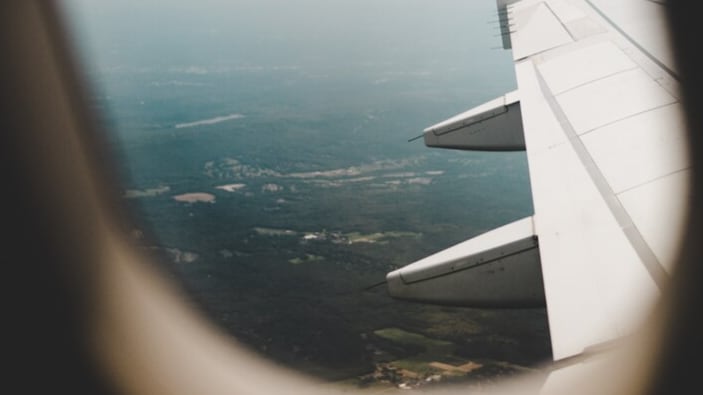 La ventana del avión con la vista de los campos verdes de arriba y el ala derecha