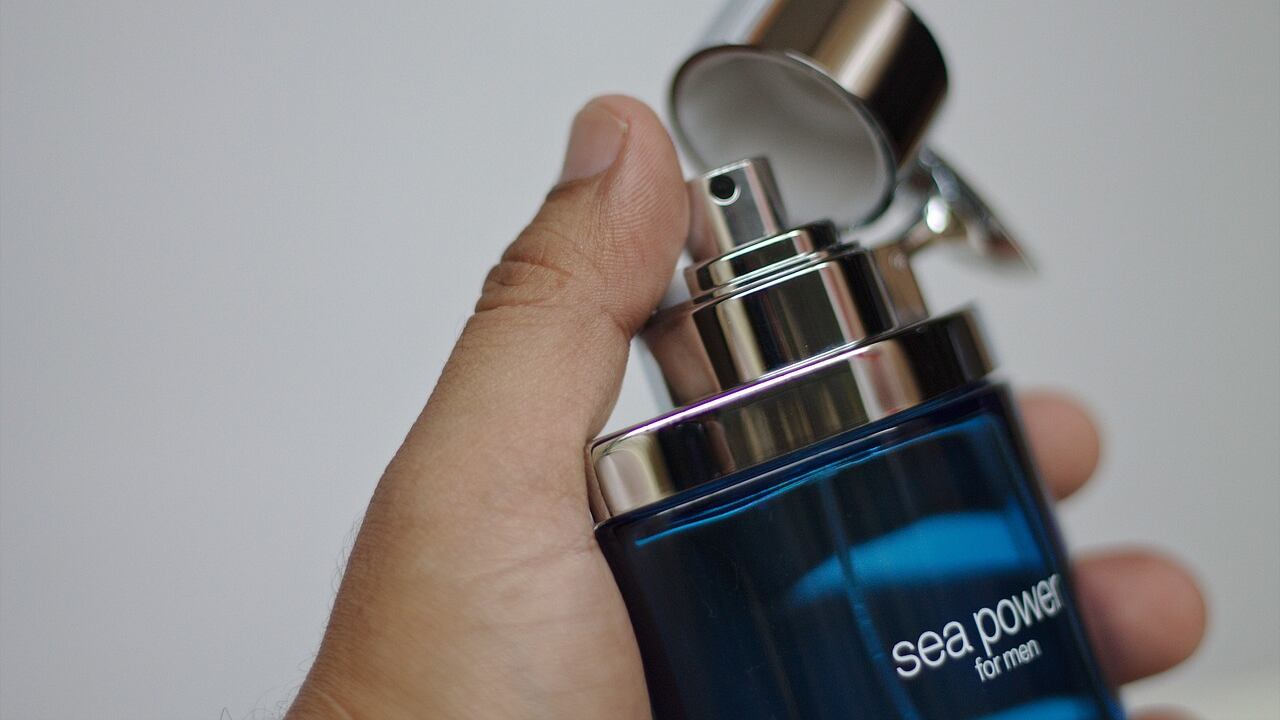 Mão masculina segurando frasco de perfume sea power for men azul